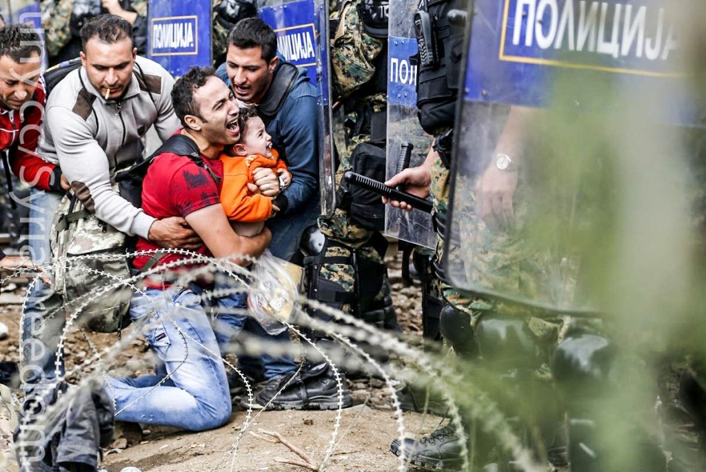 Migrant men help a fellow migrant man holding a boy as they are stuck between Macedonian riot police officers and migrants during a clash near the border train station of Idomeni, northern Greece, as they wait to be allowed by the Macedonian police to cross the border from Greece to Macedonia, Friday, Aug. 21, 2015. Macedonian special police forces have fired stun grenades to disperse thousands of migrants stuck on a no-man's land with Greece, a day after Macedonia declared a state of emergency on its borders to deal with a massive influx of migrants heading north to Europe. (AP Photo/Darko Vojinovic) (Darko Vojinovic)